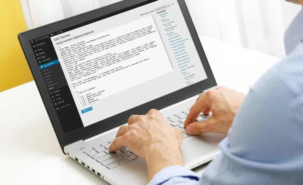 Developer working on WordPress Theme Editor code on a laptop.